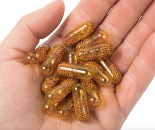 A hand holding a handful of Elixinol Life's Joints Rejoice tablets